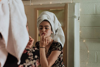 woman applying makeup in a mirror Photo by kevin laminto on Unsplash